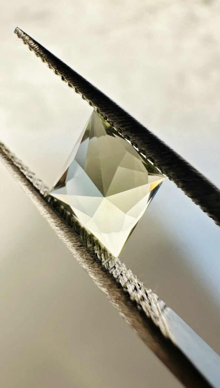 Precision cut gemstone in tweezers